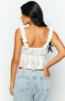 Close-up of the white top's ruffled floral strap, textured bodice, and sheer embroidered lower panel with elasticated waist