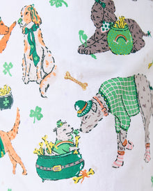 Close-up of the pajama print with dressed dogs, clovers, pots, rainbows, and an embroidered gold bone