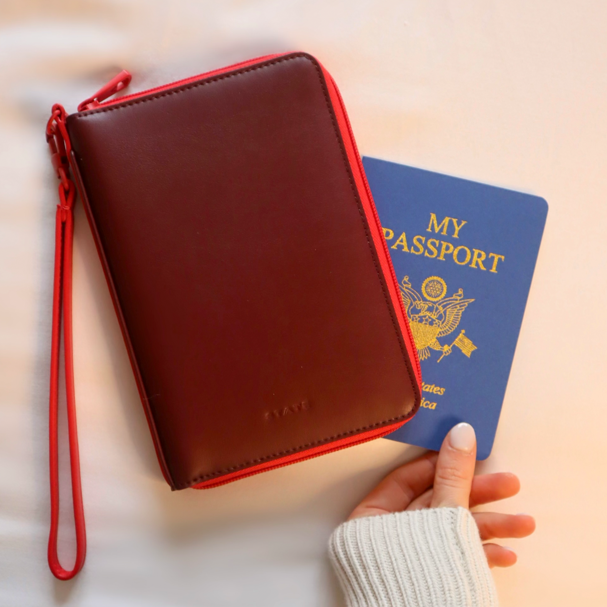 Girl holding STATE Bags passport holder in burgundy