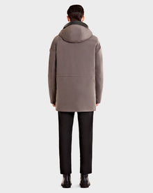 A person is seen from behind wearing the Rudsak DENT - CA EN 6119515 ELEFANTE gray mid-length parka with leather trim, paired with black pants and shoes, standing against a plain light gray background.