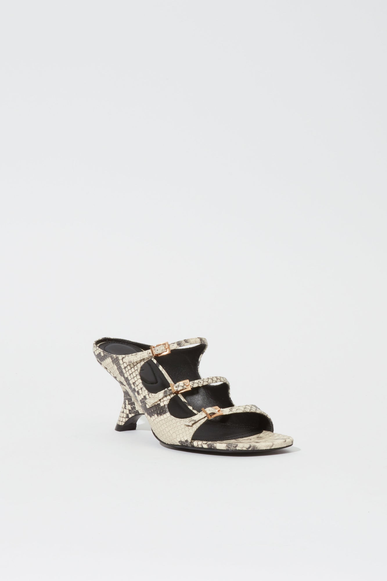 Beige and black snake print leather mule with three buckle straps and a curved heel, shown from the side.