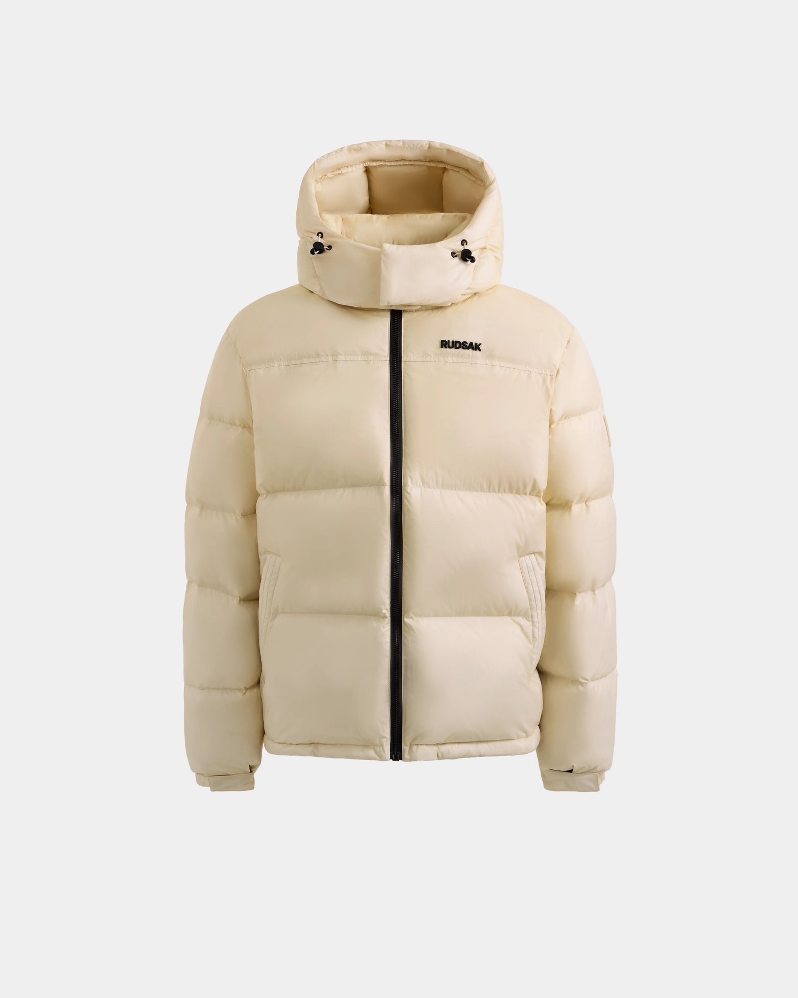 The Rudsak STEFANO - 6125574 Vanilla is a beige men’s quilted down puffer with a hood, black zipper, and small RUDSAK logo on the left chest, shown against a white background as quality winter outerwear.