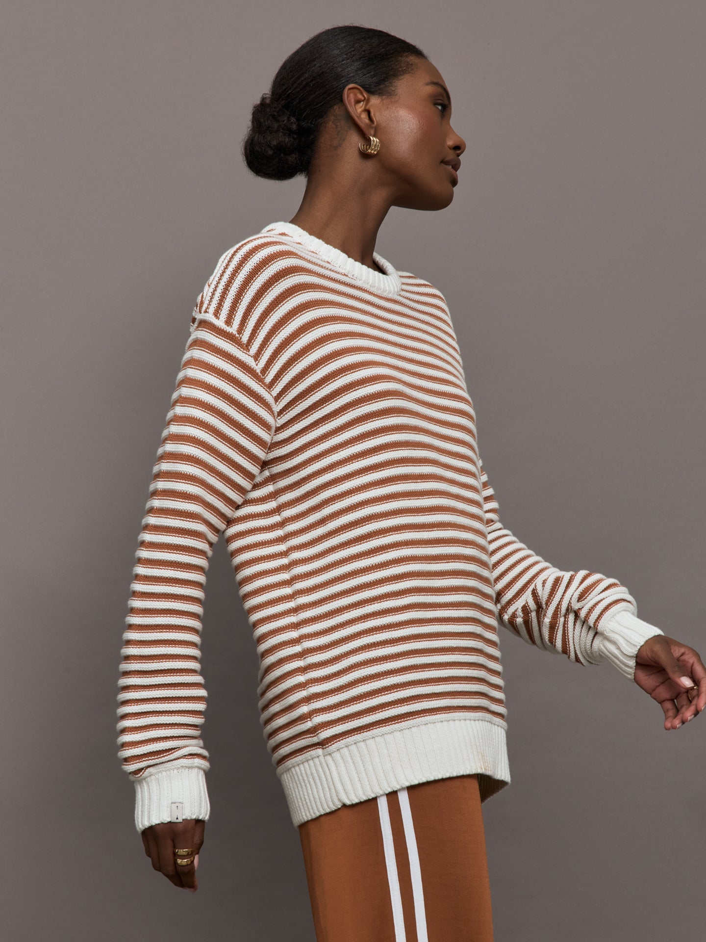 Model is wearing a brown/white horizontally striped oversized sweater.