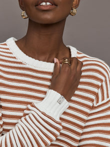 Model is wearing a brown/white horizontally striped oversized sweater.