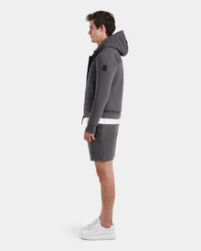 A man stands in profile wearing the Rudsak DEE MAT - 6124028 Grey lightweight down jacket, matching gray shorts, a white t-shirt, and white sneakers against a plain white background.