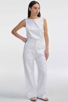 Woman wearing a white sleeveless top and wide-leg pants on a white background