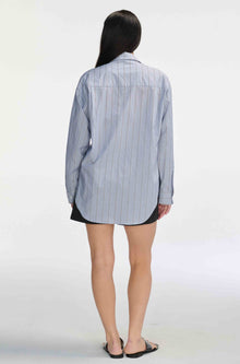 Woman wearing a black and navy striped shirt with black shorts against a light grey background