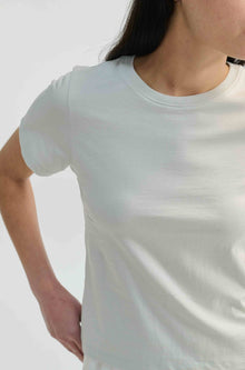 Person wearing a plain white t-shirt against a light gray background