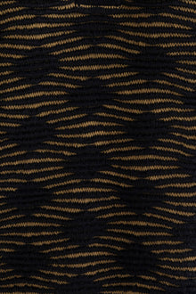 Close-up of the Amelie Polo highlighting the monochromatic textured pattern in golden and black, made from a midweight baby alpaca blend.