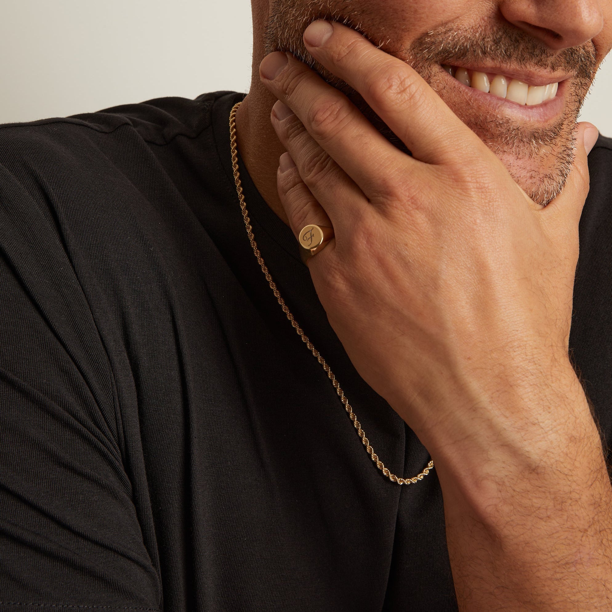 Model. Man wearing a gold necklace with a plain background