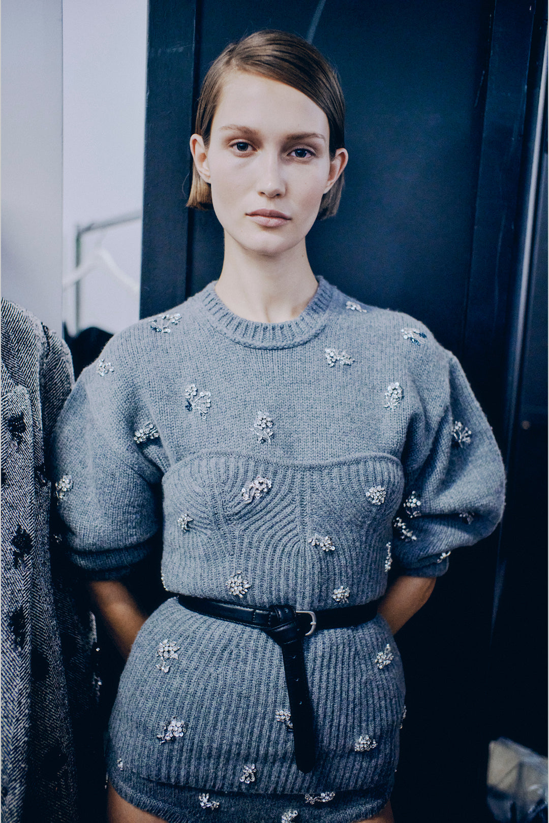 Gray knit sweater with scattered silver beaded embellishments, crew neckline, and ribbed texture throughout.