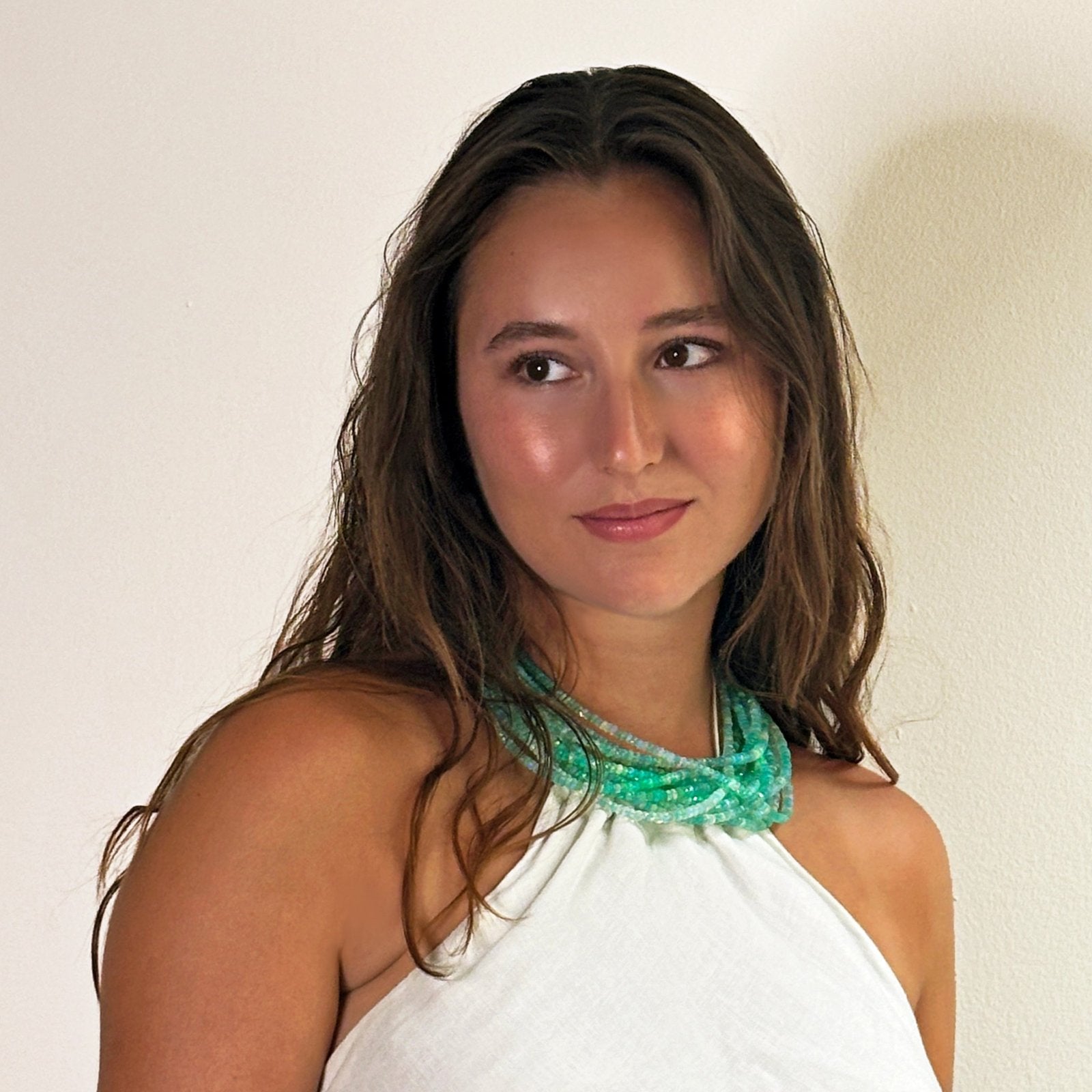 Shimmering beaded necklace made of faceted opals in shades of Blue, Teal, green and pale blue on a gold linking ovals clasp Styled together on a neck