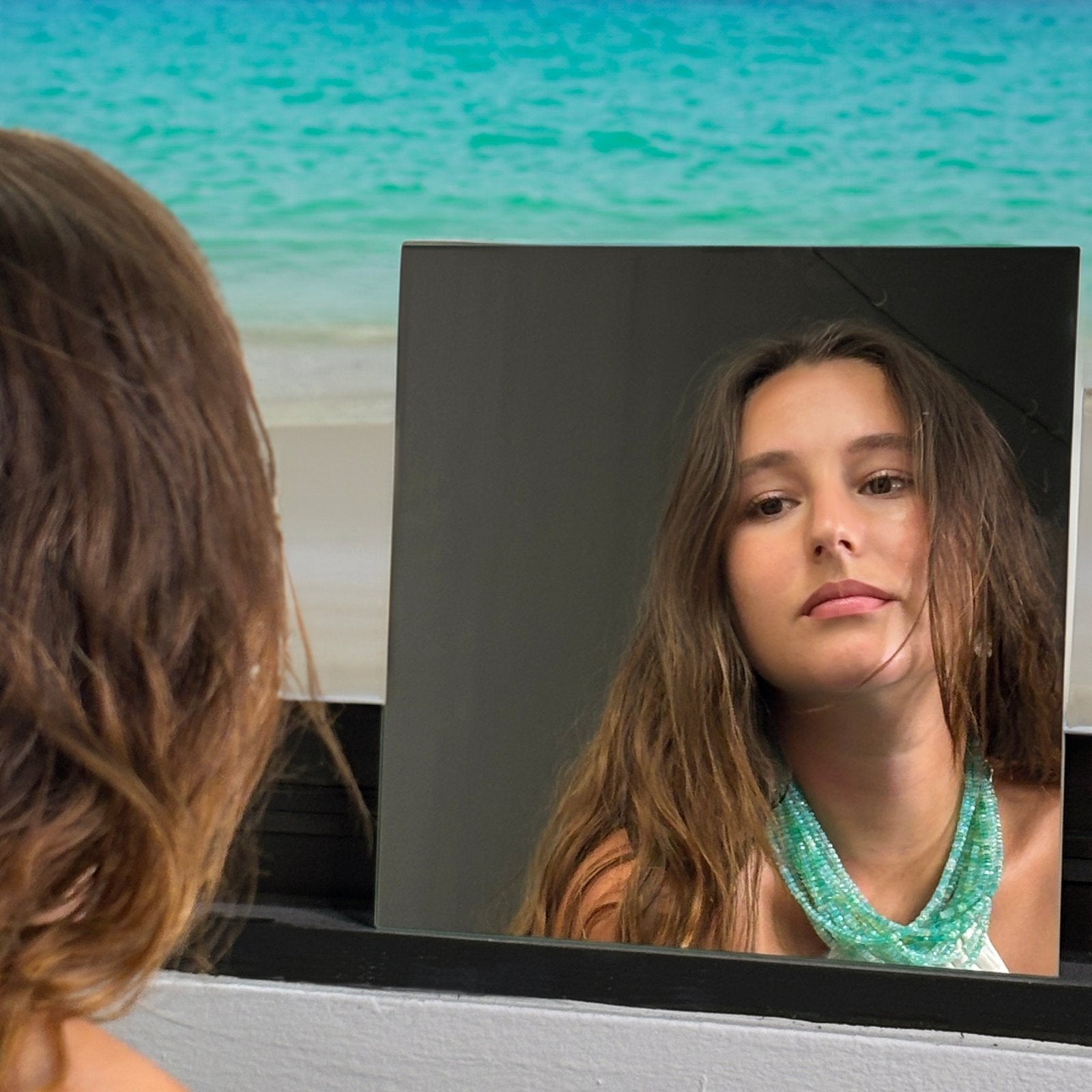 Shimmering beaded necklace made of faceted opals in shades of Blue, Teal, green and pale blue on a gold linking ovals clasp Styled on a neck layered together, in the reflection of a mirror