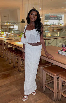 Front view of a lightweight white crinkled maxi skirt with an elasticated waist and flowy silhouette
